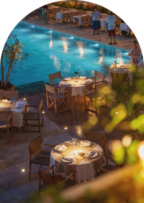 A candlelit table for two beside a pool at dusk at a boutique hotel in Albania